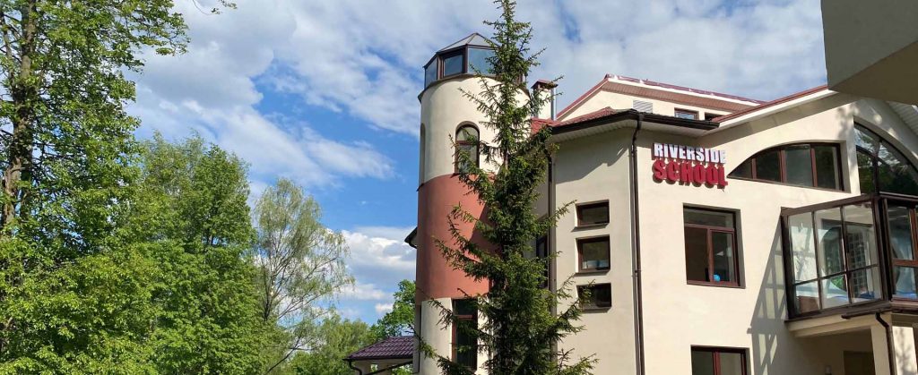 Здание Riverside School в окружении деревьев