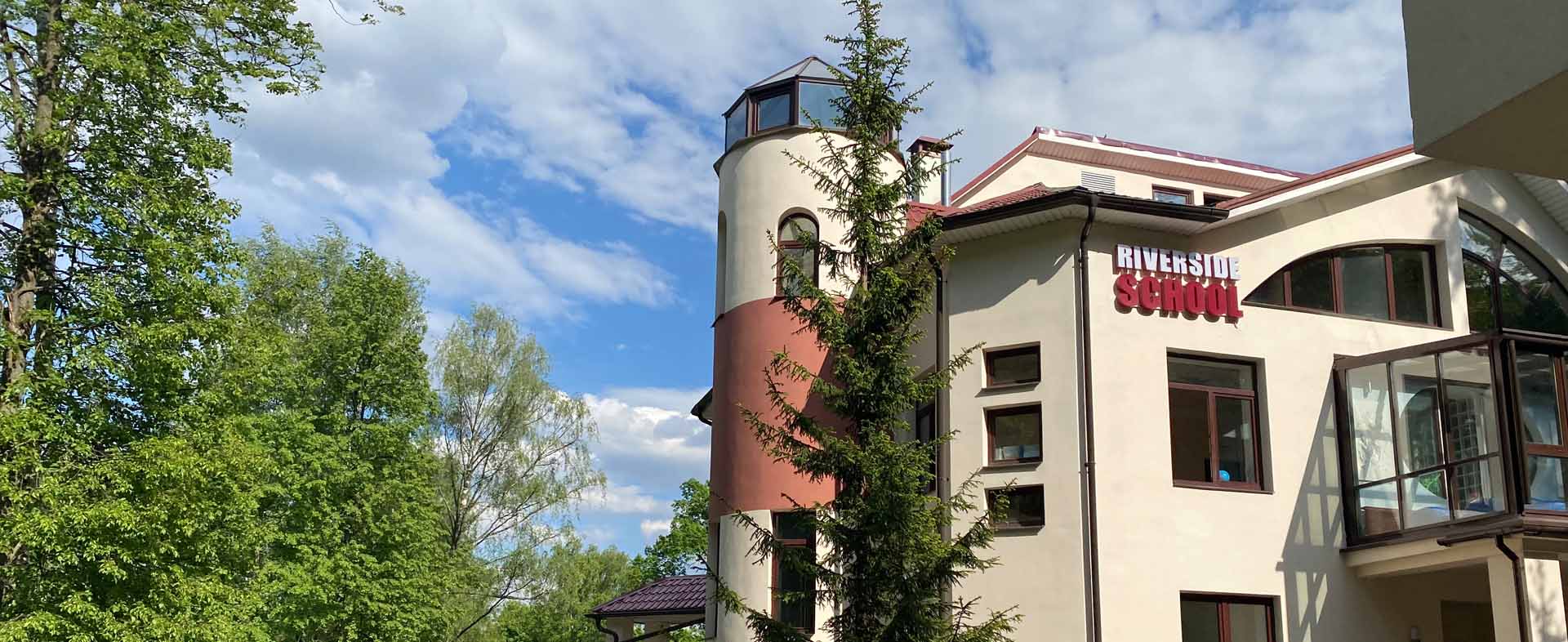 Здание Riverside School в окружении деревьев