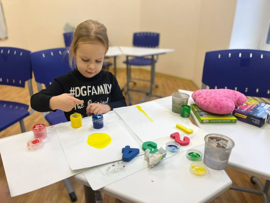 Ребёнок рисует красками в детском саду Riverside / A child painting at Riverside Kindergarten