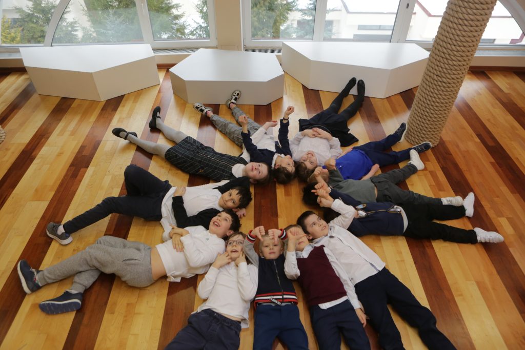 Ученики Riverside лежат в кругу в школьном зале / Riverside pupils lying in a circle in the school hall